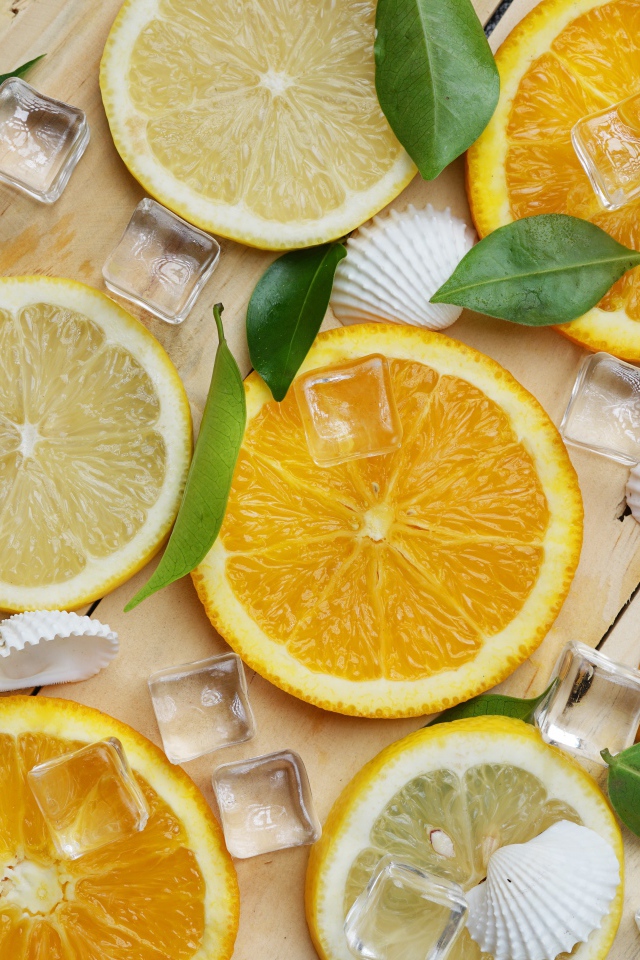 Кусочки апельсина и лимона на столе с кубиками льда и ракушками