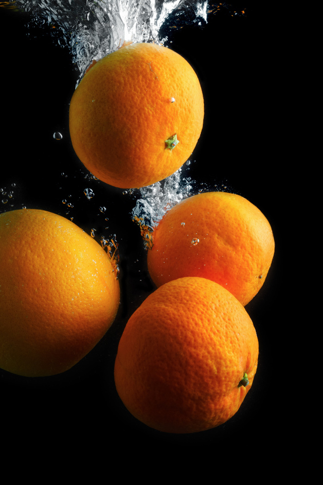 Мандарины и апельсины в воде на черном фоне