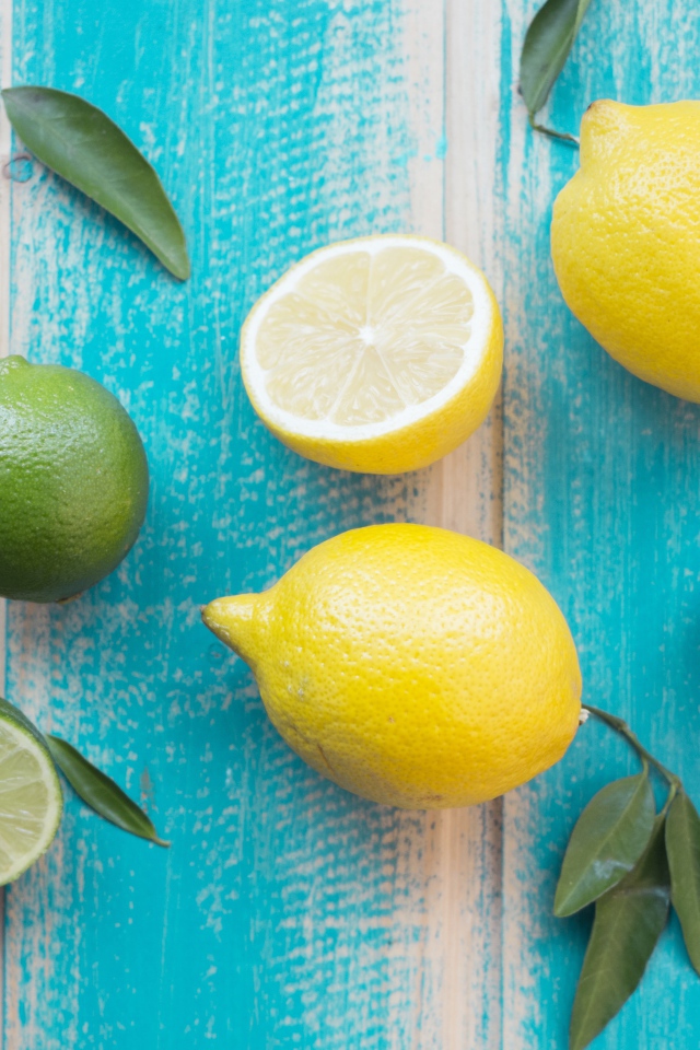 Желтые лимоны и зеленые плоды лайма на столе 