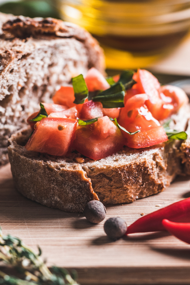 Черный хлеб с кусочками помидора на столе с острым красным перцем