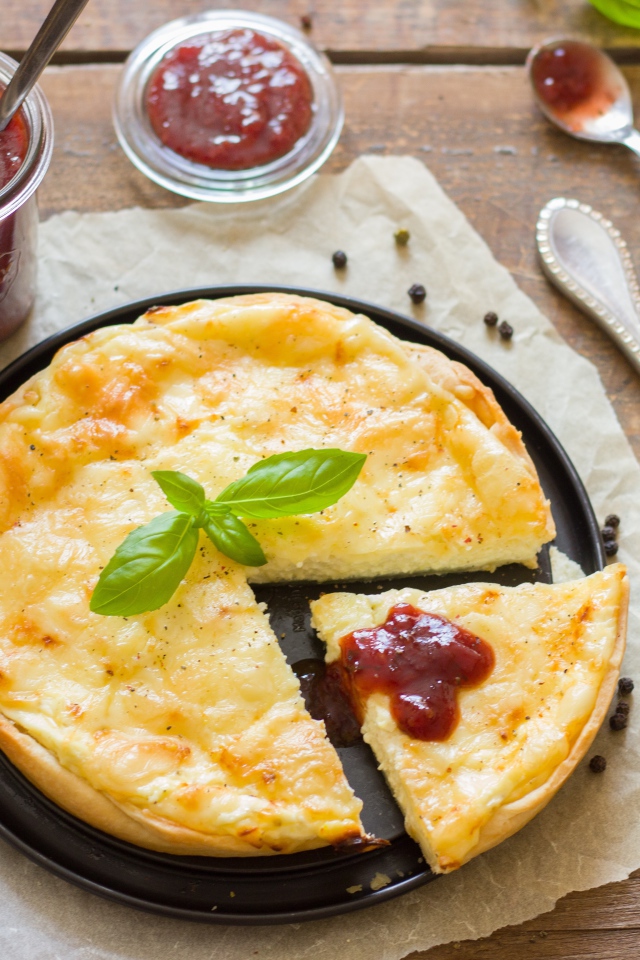 Cheese pie on the table with ketchup and basil