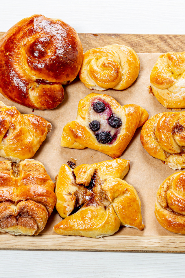 Разная свежая выпечка на доске на белом фоне