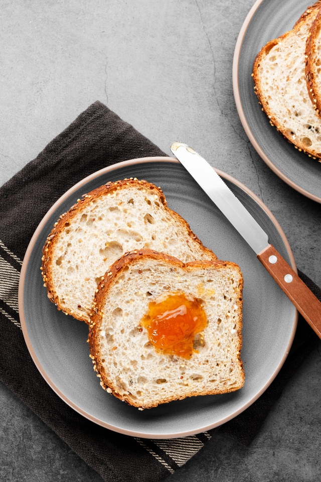 Куски хлеба с джемом на сером столе 