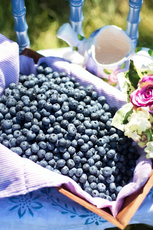 Корзина со спелыми ягодами черники стоит на столе