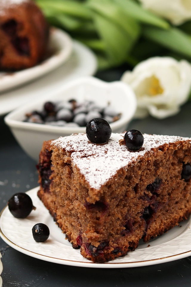 Кусок пирога со смородиной на столе с тюльпанами 