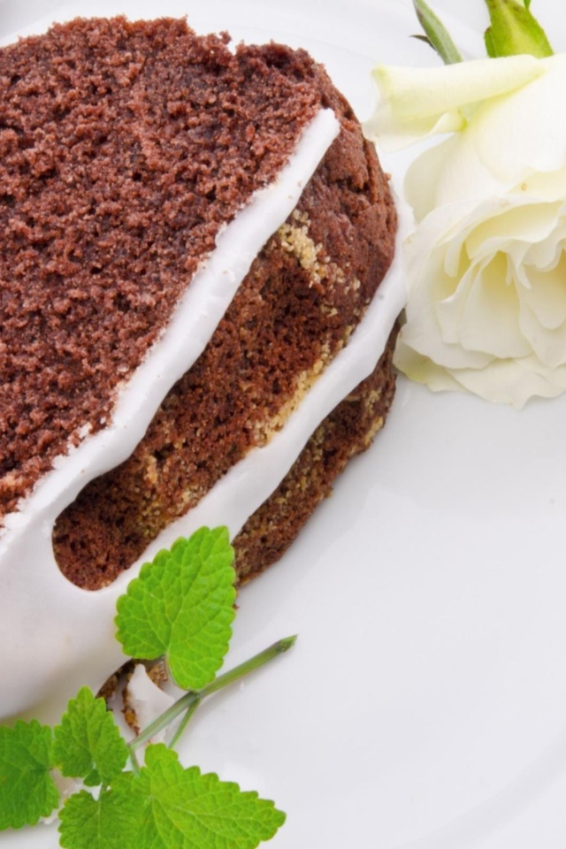 Кусок шоколадного пирога на тарелке с белой розой 