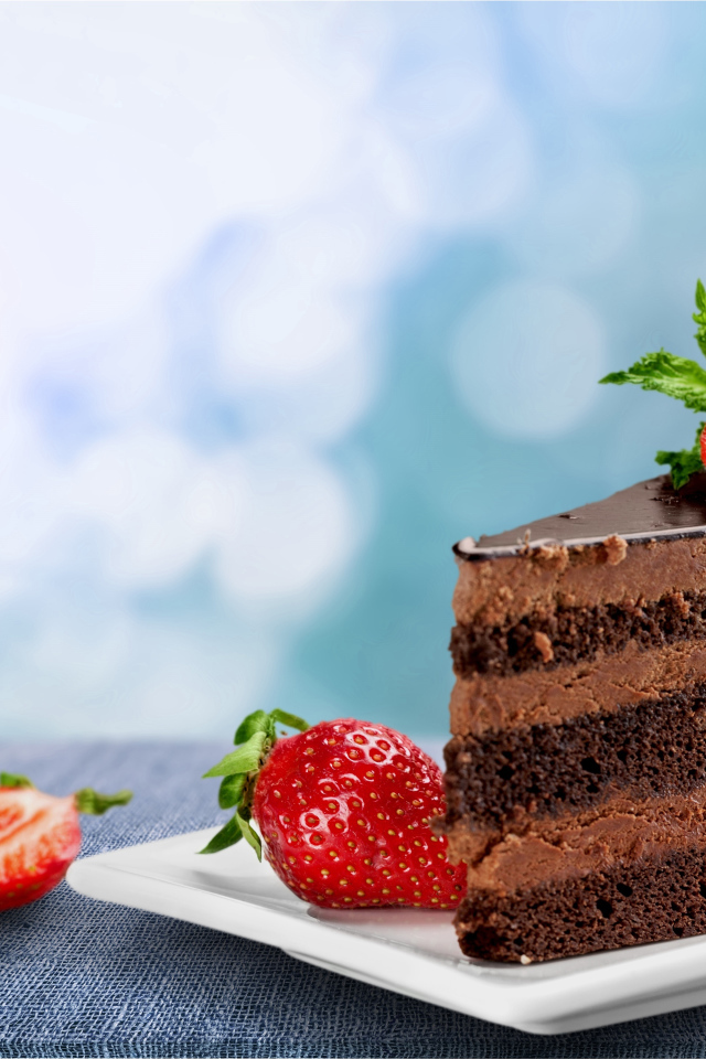 Кусок аппетитного торта с шоколадным кремом и клубникой 