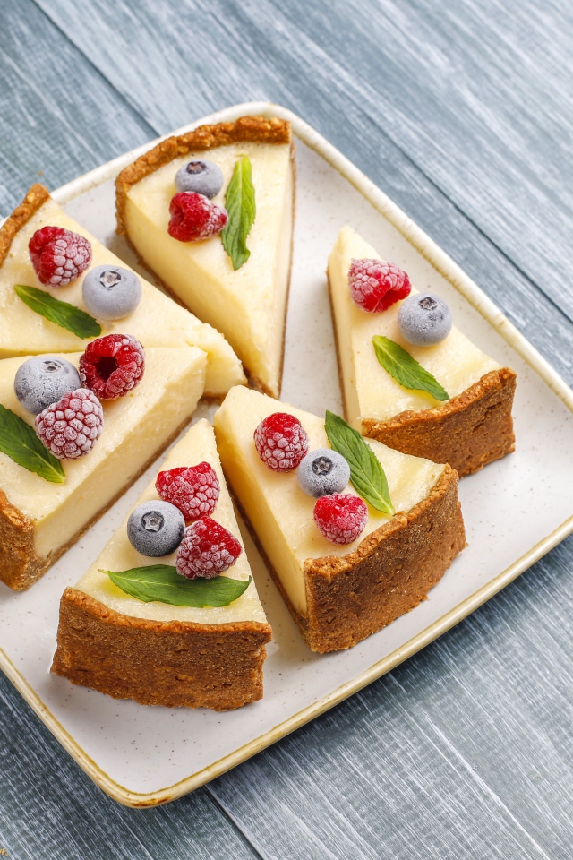 Аппетитный чизкейк с ягодами нарезан кусками на тарелке 