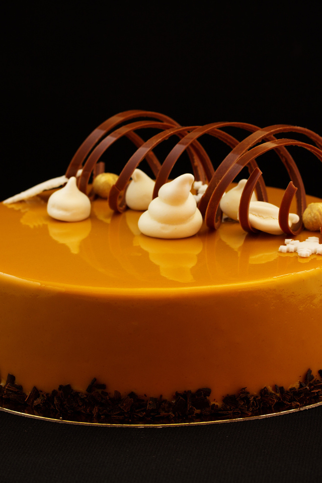 Красивый глянцевый оранжевый торт на черном фоне