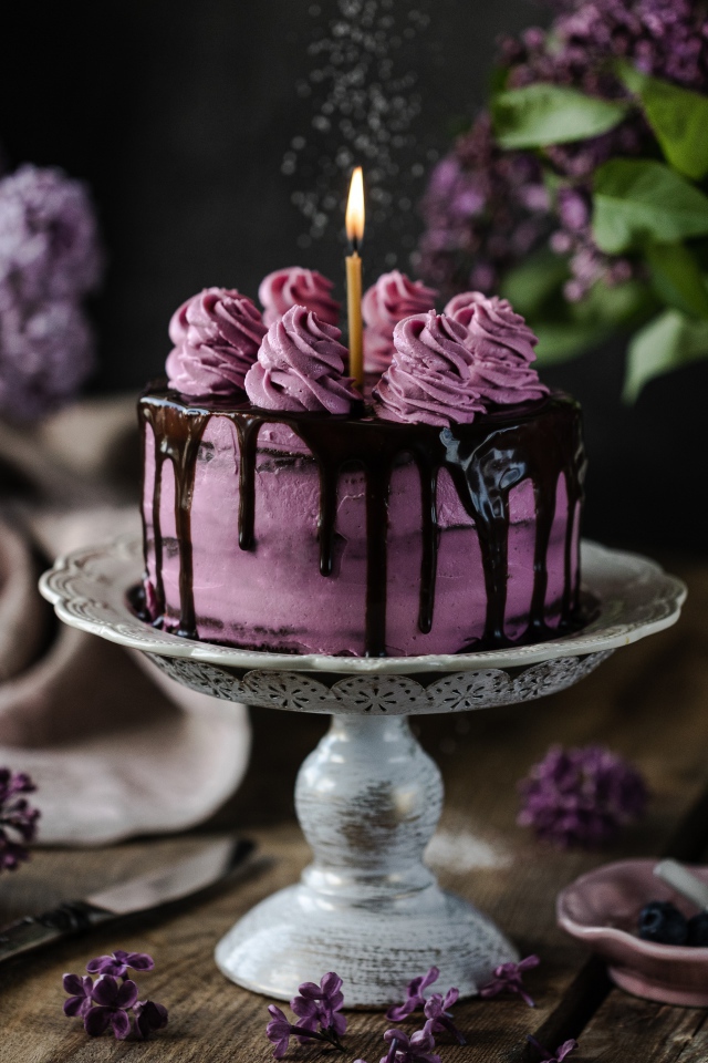 Ягодный торт со свечой на столе с сиренью 