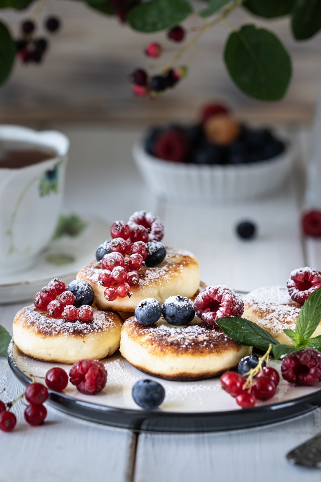 Сырники на столе с ягодами и чаем на завтрак