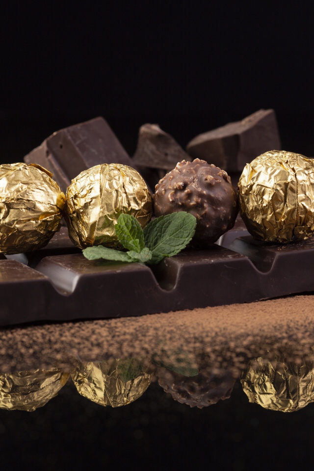Плитки черного шоколада с конфетами на столе 