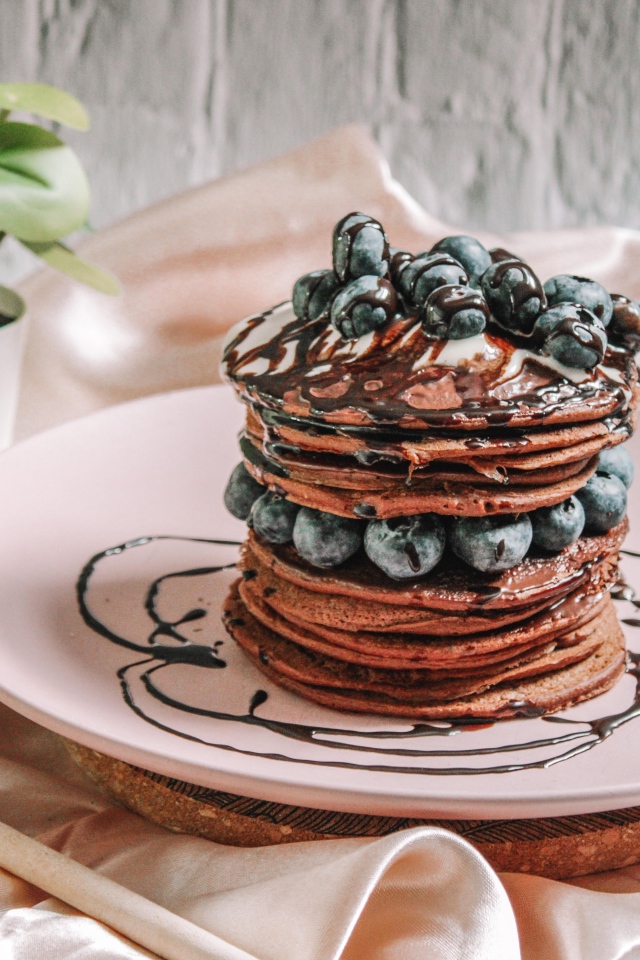 Шоколадные оладьи с ягодами черники на белой тарелке