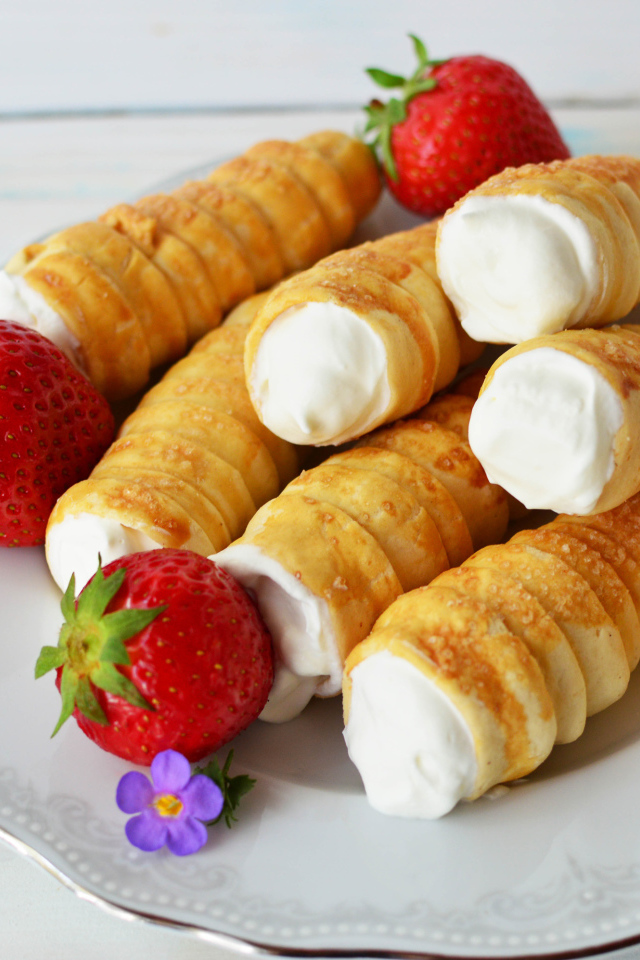 Пирожные с кремом на тарелке с клубникой