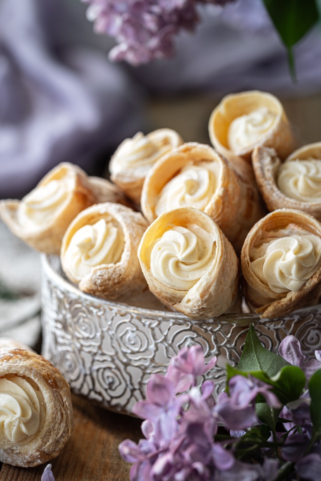 Трубочки с кремом на столе с цветами сирени