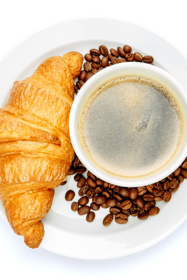 Чашка кофе на белой тарелке с круассаном и зернами, вид сверху 