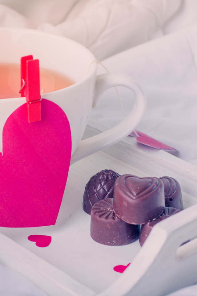 Чашка кофе с красным сердцем и шоколадными конфетами 