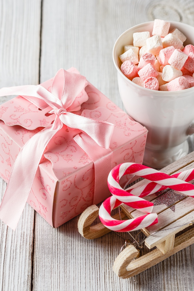 Чашка с маршмеллоу на столе с игрушечными санками и подарком