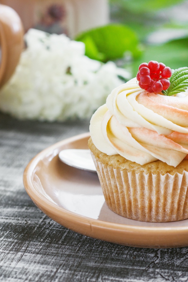 Кекс с кремом и малиной на столе