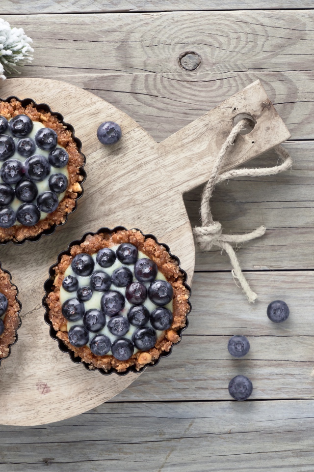 Кексы с кремом и ягодами черники на столе с чайными ложками