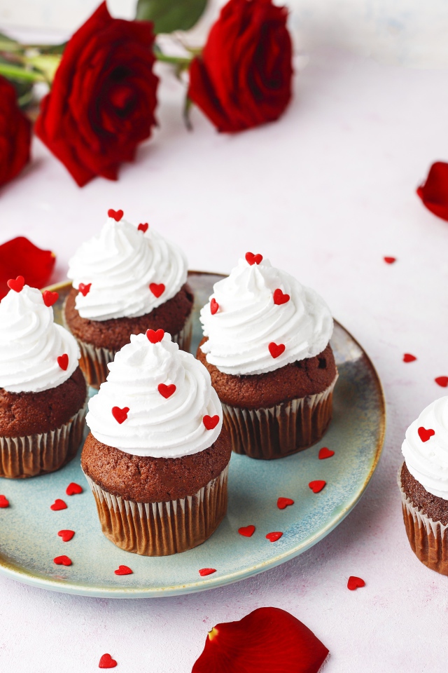 Кексы с кремом на столе с букетом роз 