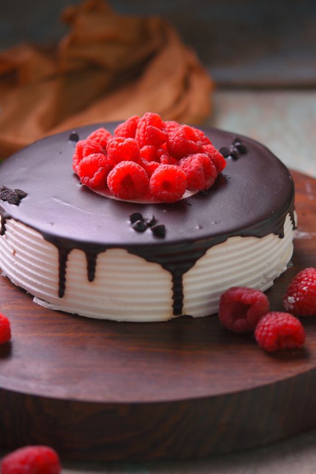 Вкусный торт с шоколадом и малиной на столе с цветами хризантемы 