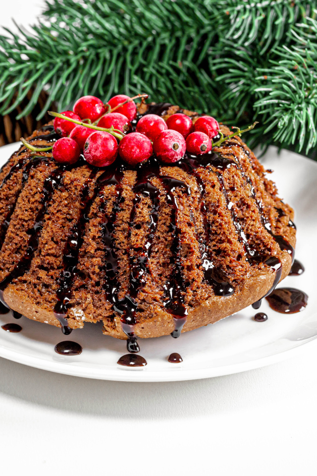 Вкусный кекс с шоколадом и красной смородиной на столе с еловой веткой и шишками