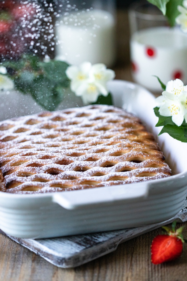 Вкусный клубничный пирог с сахарной пудрой на столе с цветами жасмина