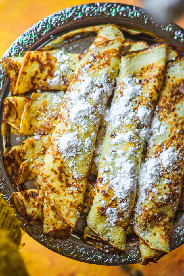 Вкусные тонкие блины с сахарной пудрой на блюде