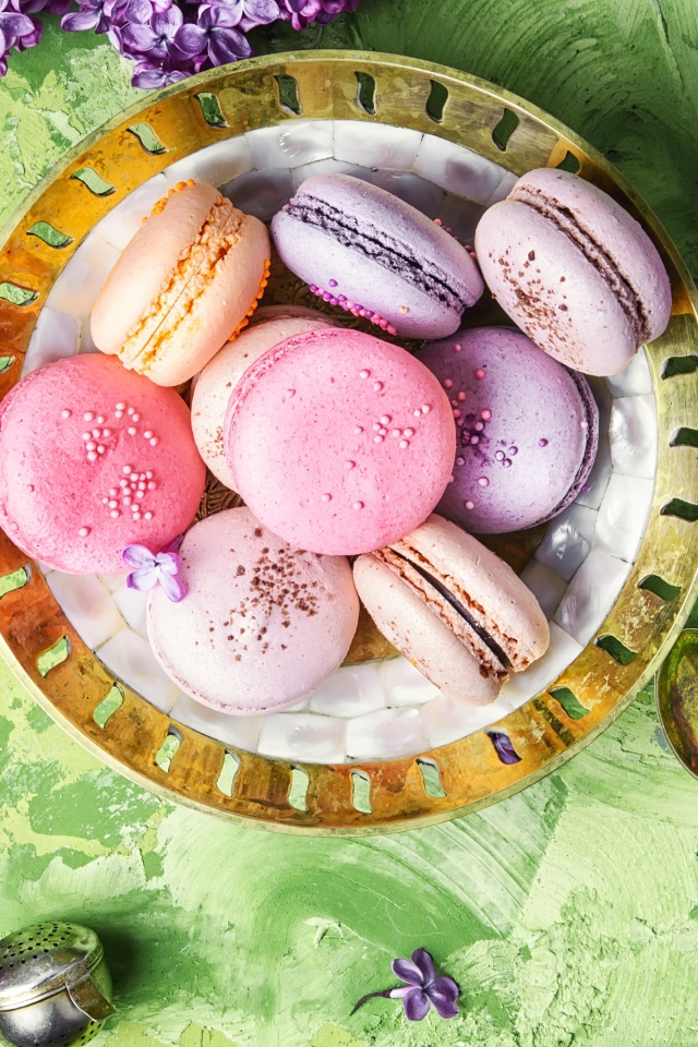 Разный десерт макарон на столе с цветами сирени 