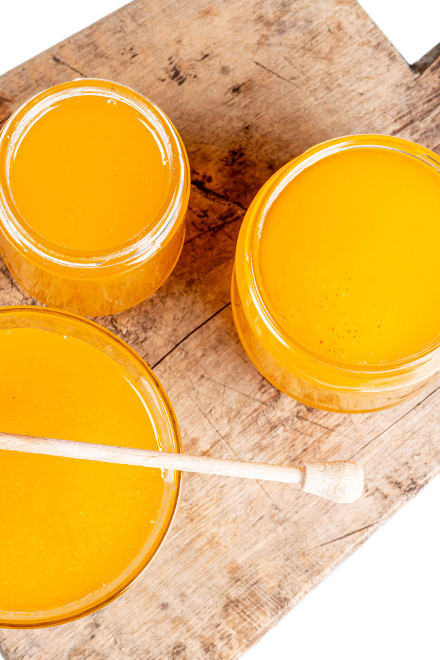 Свежий мед в банках на деревянной доске на белом фоне