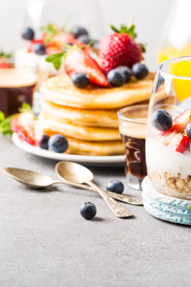 Оладьи на столе с ягодами, мюсли и кофе