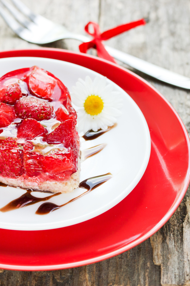 Пирожное с клубникой в форме сердца на тарелке с ромашками