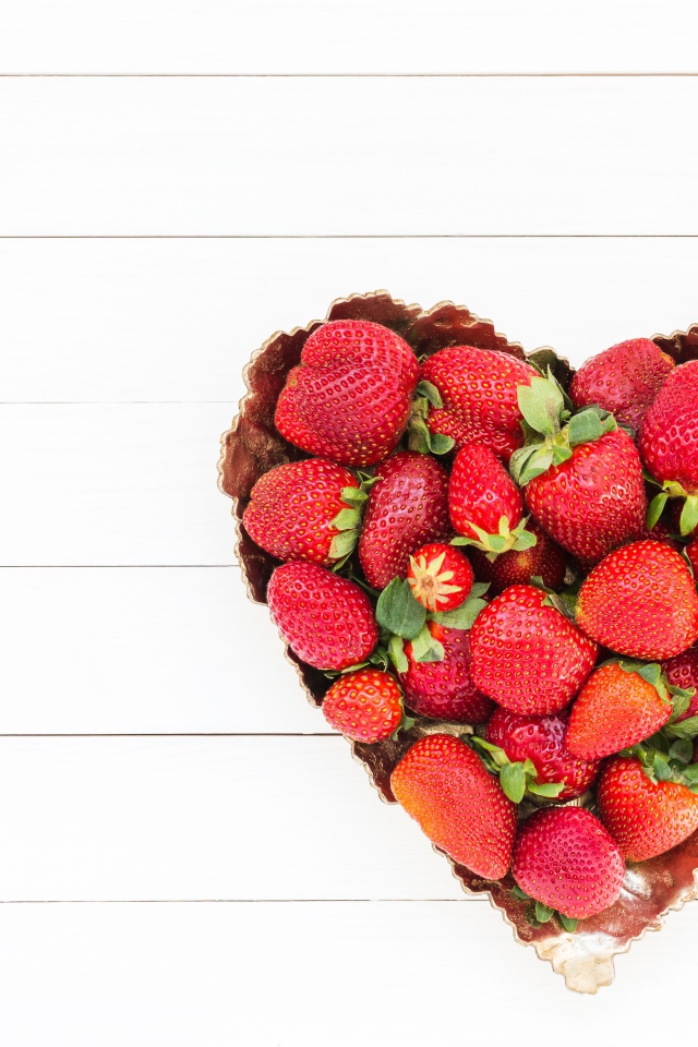 Пирожное в форме сердца с клубникой на белом фоне