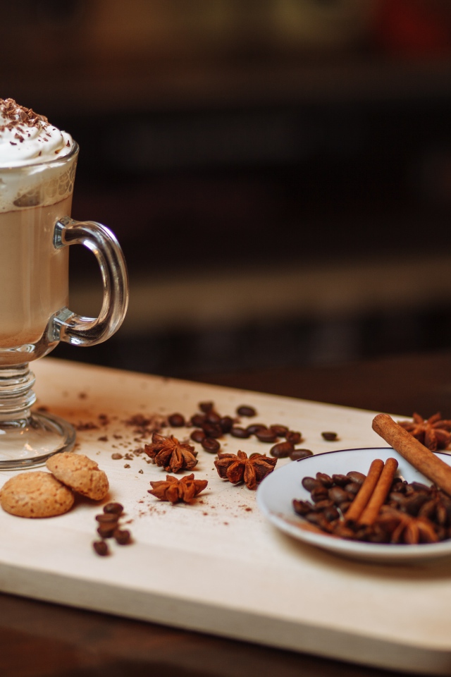 Горячее какао со сливками на столе с печеньем, зернами кофе и пряностями 
