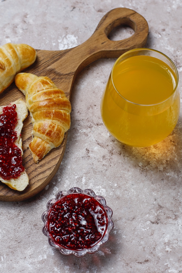 Сок на столе с круассанами и джемом