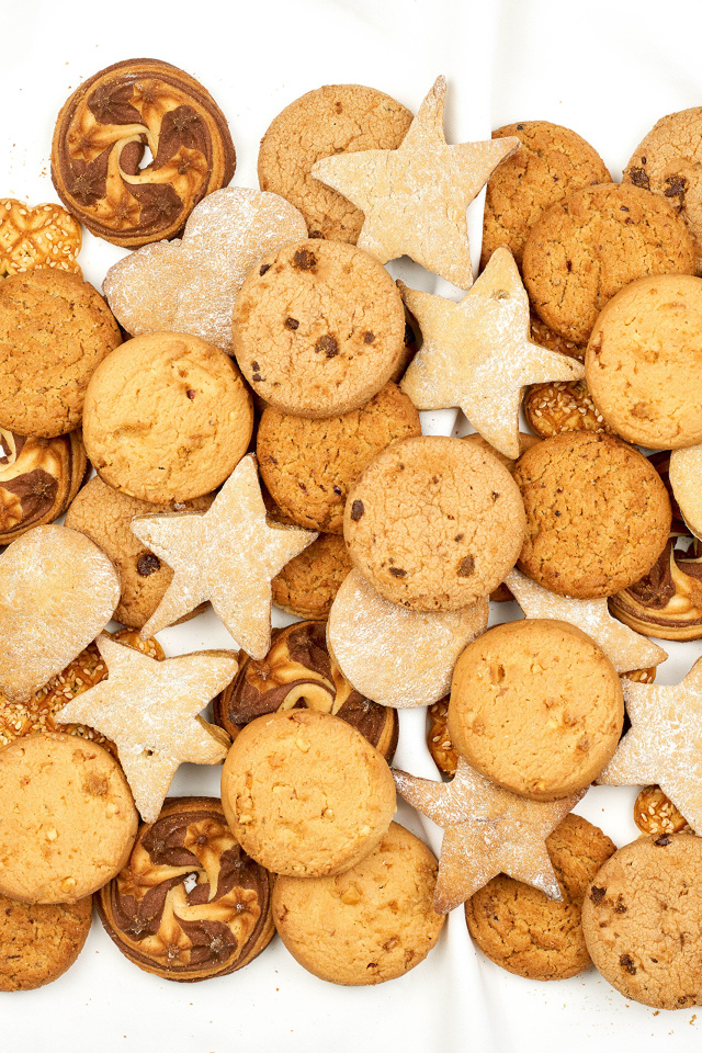 Много песочного печенья разной формы на белом фоне