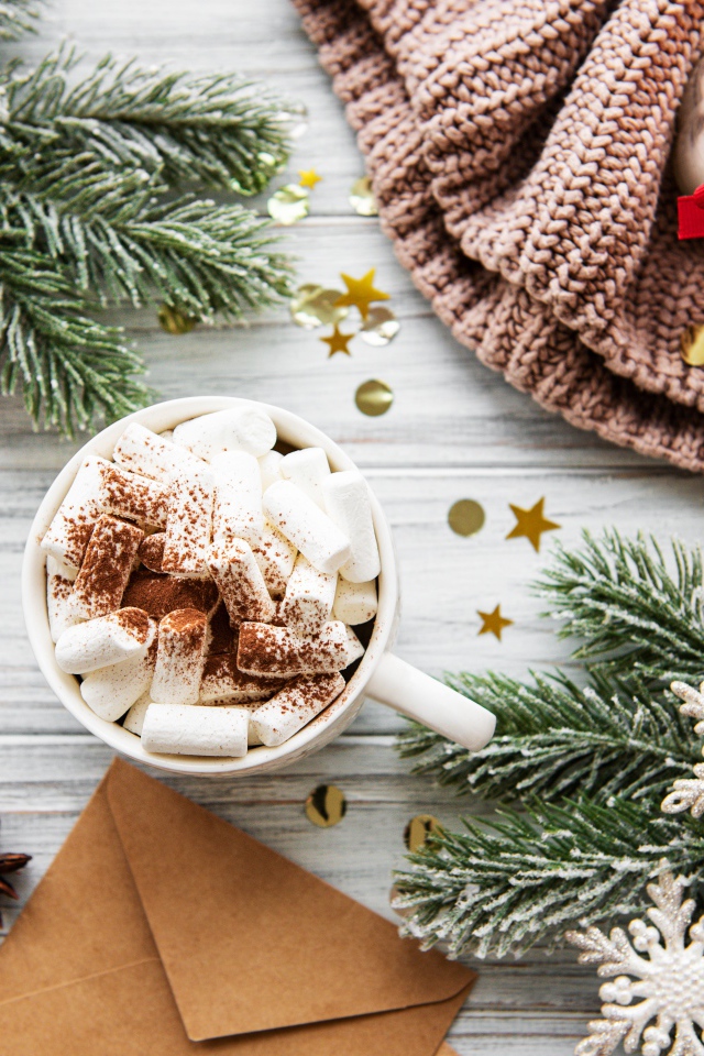 Кружка с маршмеллоу на столе с еловыми ветками и свечой