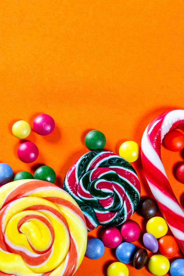 Разноцветные конфеты на оранжевом фоне