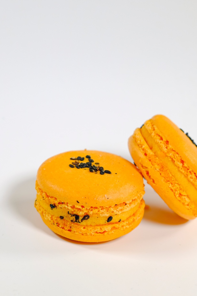 Оранжевый десерт макарон на сером фоне