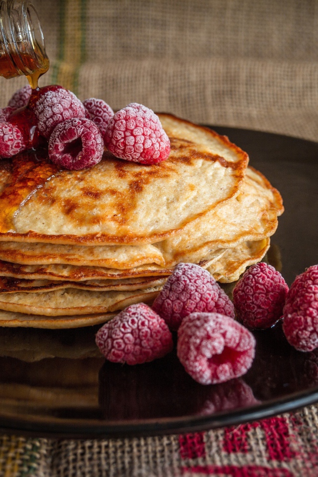 Блины с сиропом на тарелке с малиной