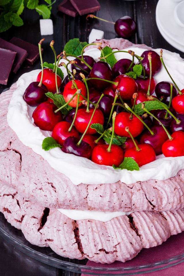 Торт Павлова со сливками и ягодами черешни на столе