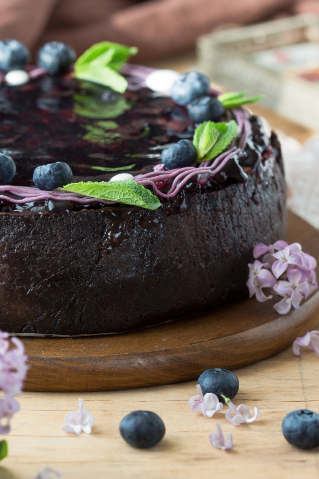 Пирог с джемом и ягодами черники на столе с сиренью 