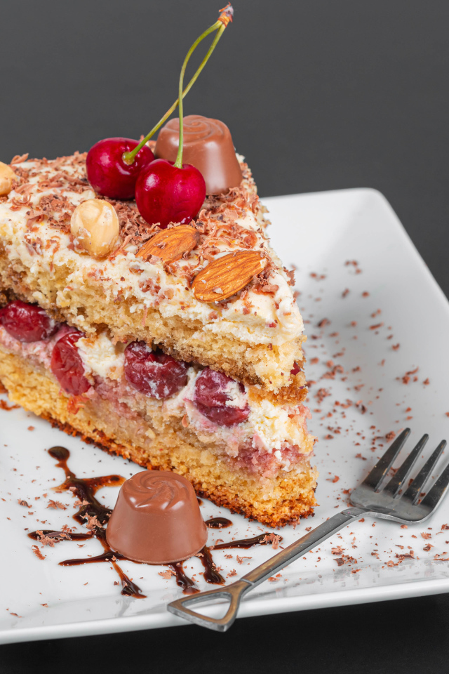 Кусок торта с ягодами вишни и миндальным орехом