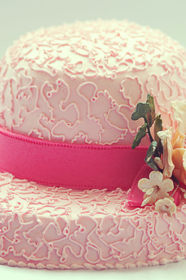 Розовый торт в виде шляпы на столе 