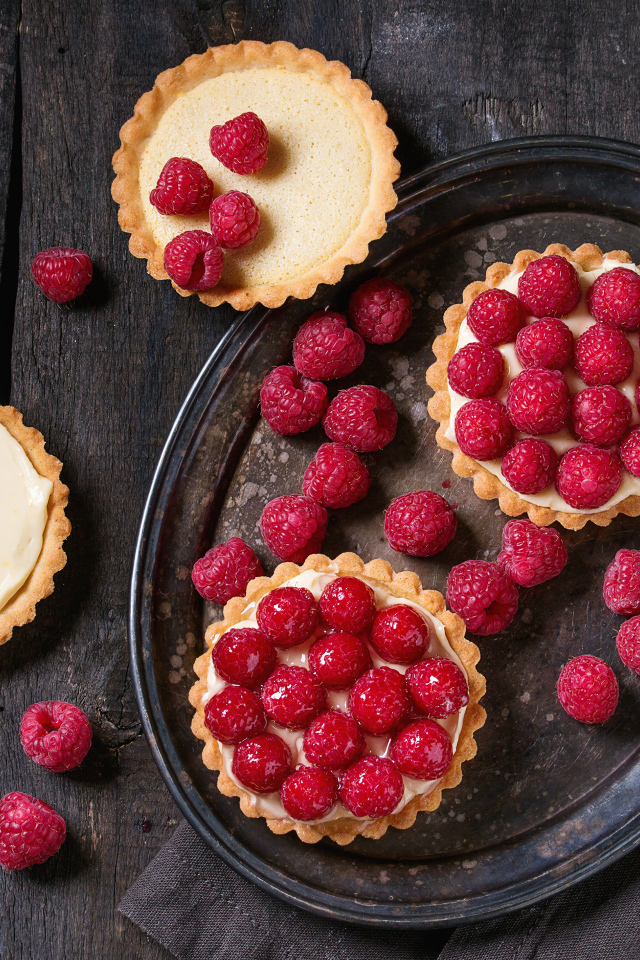 Кексы с кремом на блюде с малиной 