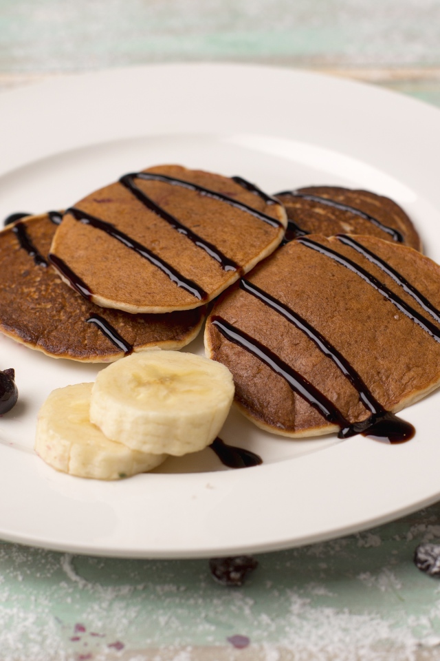 Румяные оладьи с бананом на белой тарелке 