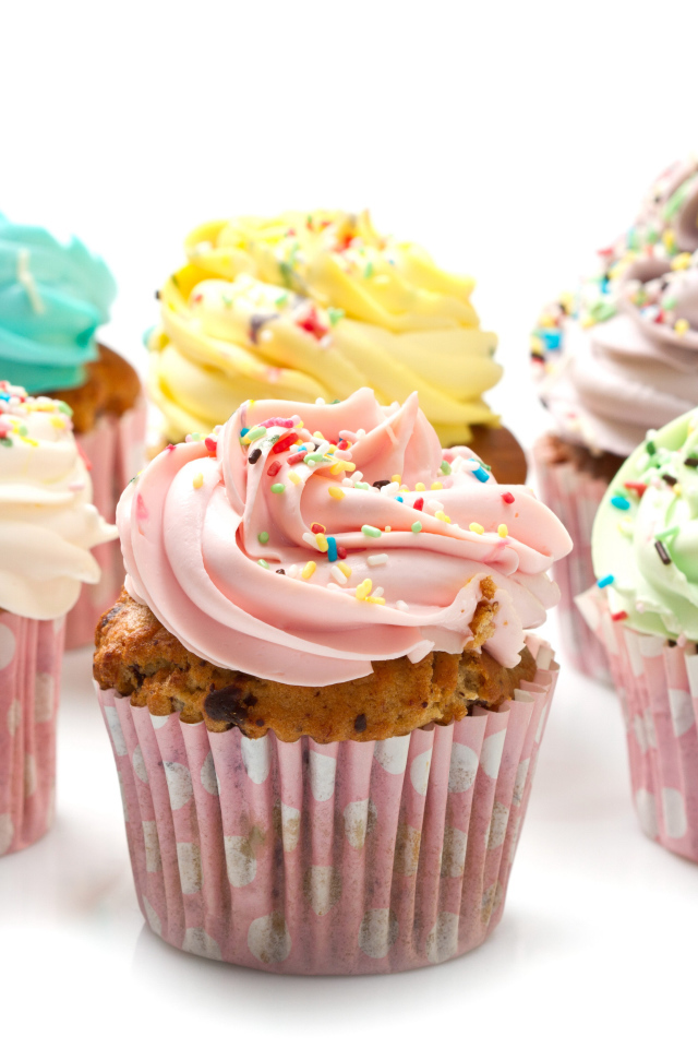 Сладкие кексы с кремом и посыпкой на белом фоне