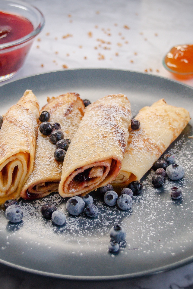 Сладкие тонкие блинчики с ягодами черники на столе с джемом