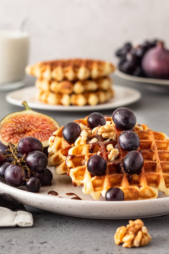 Сладкие вафли на тарелке с инжиром и виноградом